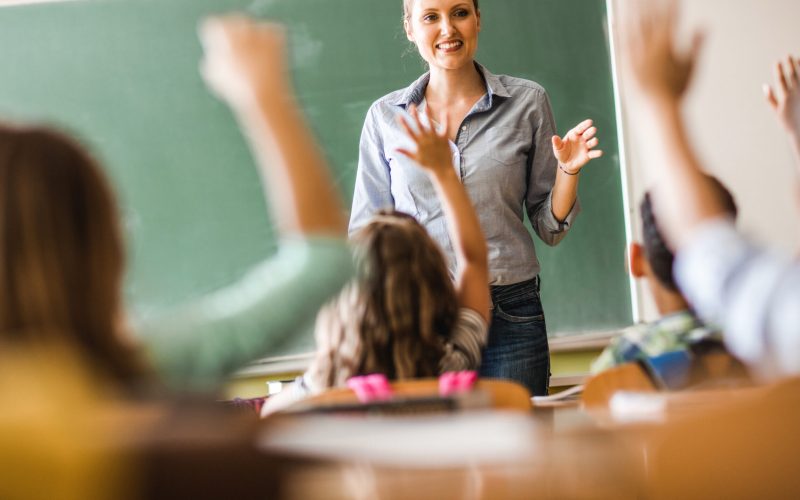 Lachende weibliche Lehrerin befragt ihre Klasse